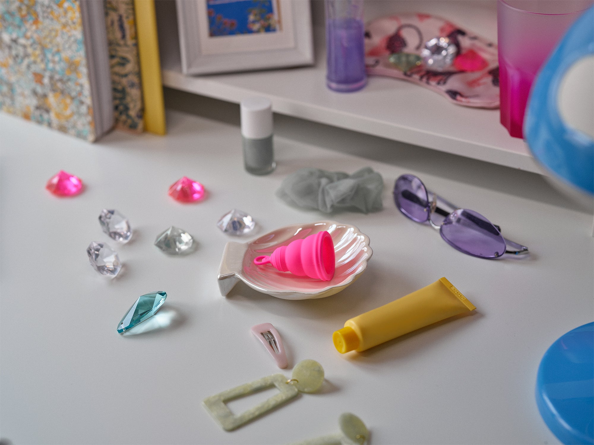 a pink menstrual cup in a shell next to hair clips, glasses and jewels .Our classic Itimina lily one period cup . This menstrual cup is made from reusable soft silicone, the perfect eco-choice for sister's who want a safe, healthy, non toxic, latex free, BPA free and waste free period product.provides 8 hours of protection. הגביעונית הכי טובה ונוחה בישראל, תהני מכוס מחזור שלך