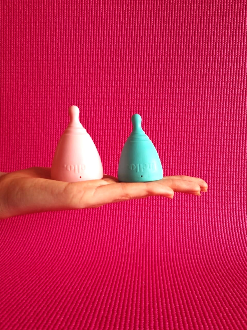 HANDS HOLDING MENSTRUAL CUPS ON PINK BACKGROUND